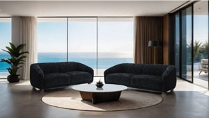 Aaron Contemporary Black Boucle Chair Sloped Arms Modern living room with two dark gray sofas, a round coffee table, and large windows overlooking an ocean view.