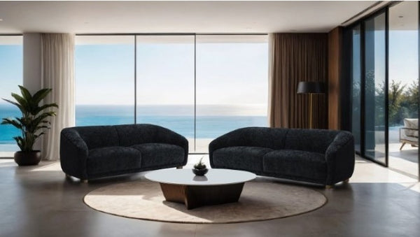 Aaron Contemporary Black Boucle Chair Sloped Arms Modern living room with two dark gray sofas, a round coffee table, and large windows overlooking an ocean view.
