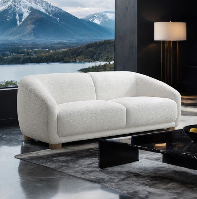 Aaron Contemporary White Boucle Loveseat Sloped Arms White sofa in a modern living room with a scenic view of mountains and water.