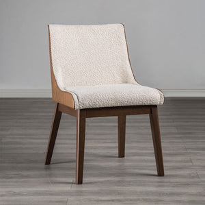 Abram Mid Century Modern Walnut Dining Chair A modern dining chair with a cream textured fabric upholstered seat and backrest, supported by a light wood frame and dark brown tapered legs, set against a neutral gray wall and wood-look floor.