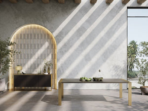 Alessa Modern Dining Table - Brass & Wenge Modern interior design with a table and decorative items against a concrete wall.
