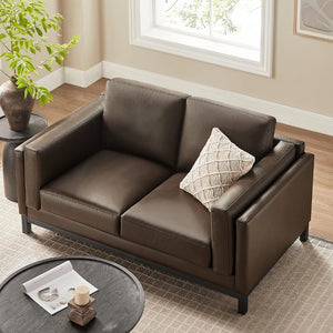 Amadeo Espresso Vegan Leather Modern Loveseat Brown leather sofa in a living room setting with a pillow and small table.