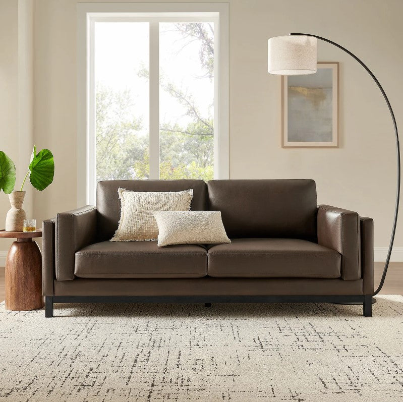 Amadeo Espresso Vegan Leather Modern Sofa Brown leather sofa in a living room with a lamp and window in the background