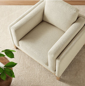 Amadeo Ivory Deep Seat Comfort Modern Fabric Chair Beige armchair on a textured beige carpet with a plant in the corner
