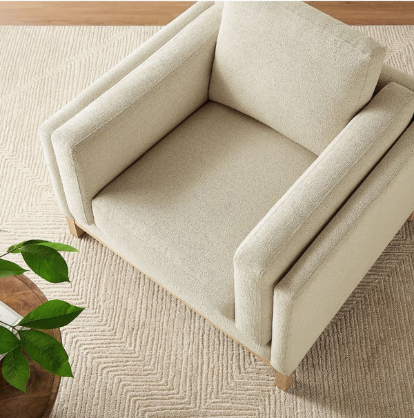 Amadeo Ivory Deep Seat Comfort Modern Fabric Chair Beige armchair on a textured beige carpet with a plant in the corner