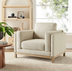 Amadeo Ivory Deep Seat Comfort Modern Fabric Chair Beige armchair in a living room setting with a bookshelf and window in the background.