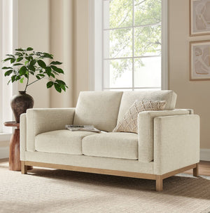 Amadeo Ivory Deep Seat Comfort Modern Fabric Loveseat Beige sofa in a living room with a plant and window in the background