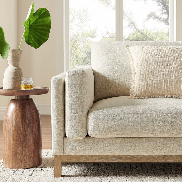Amadeo Ivory Deep Seat Comfort Modern Fabric Sofa Beige sofa in a living room with a wooden side table and decorative items.