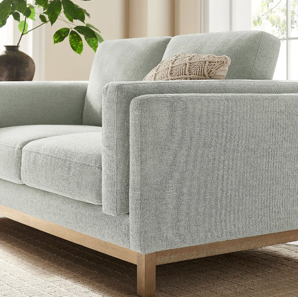Amadeo Mist Deep Seat Comfort Modern Fabric Loveseat Gray sofa with wooden legs in a living room setting