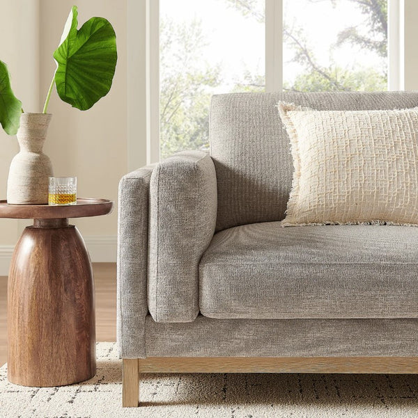 Amadeo Pewter Deep Seat Comfort Modern Fabric Sofa Gray sofa with a textured pillow in a living room setting with a wooden side table and plant.