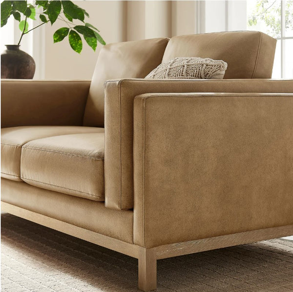 Amadeo Toast Vegan Leather Modern Loveseat Beige sofa with a textured pillow in a bright room with natural light.