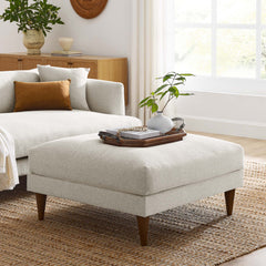 Living room with a ivory ottoman, and decorative items.