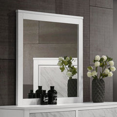 White framed mirror on a wooden wall with decorative vases and flowers.