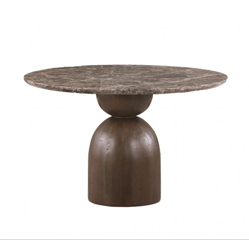 Artemos Contemporary Dark Brown Round Dining Table A round dining table with a polished stone top and a substantial dark wood pedestal base, accompanied by two matching wooden chairs with woven backs and cream upholstered seats. The table is styled with a ceramic vase of branches, glasses, and stacked plates in a softly lit dining room.