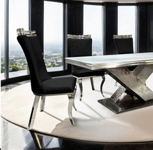Asher Silver White Cross Shaped Glam Dining Table Modern dining table with black chairs in a room with large windows.