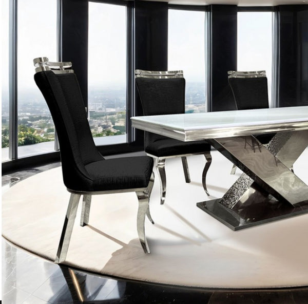 Asher Silver White Cross Shaped Glam Dining Table Modern dining table with black chairs in a room with large windows.