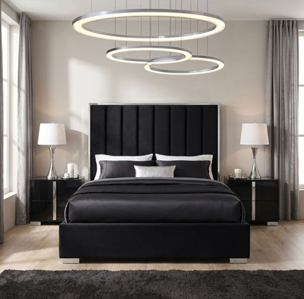 Ashysko Black Silver Fully Upholstered Bed A modern bedroom featuring a black upholstered bed with a tall segmented headboard, black nightstands, silver lamps, and a large circular ring chandelier hanging above the bed.
