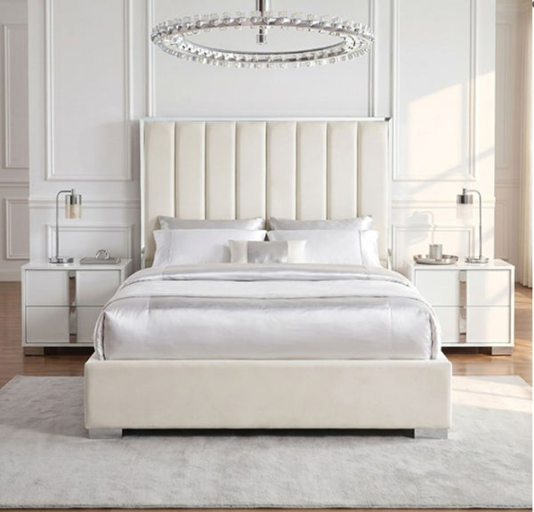 Ashysko White Silver Fully Upholstered Bed A modern cream upholstered bed with a tall channel-tufted headboard and matching footboard, styled in a bright, symmetrical bedroom with white nightstands, lamps, a light gray rug, and a crystal chandelier.