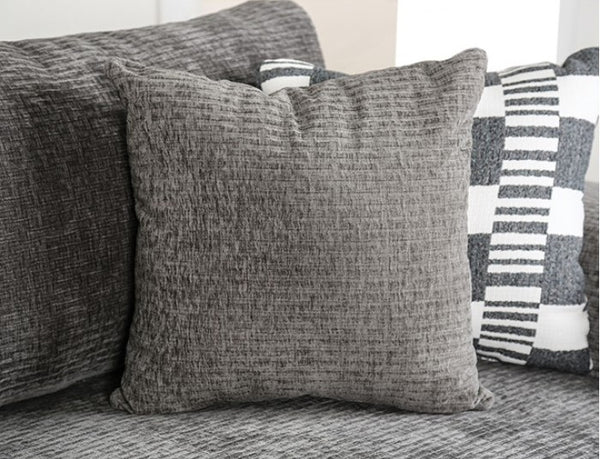 Assia L-Shape Sectional Sofa Gray textured pillows on a sofa with a striped pillow in the background