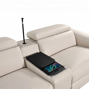 Aurelia Beige Modern Air Leather Sectional Sofa Powered Recliner A cream-colored leather sectional sofa with a center armrest console holding a black tablet and a smartphone on a charging pad, with a black floor lamp standing in the armrest compartment.
