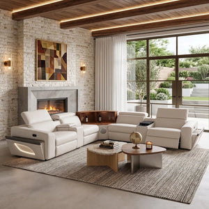 Aurelia Beige Modern Air Leather Sectional Sofa Powered Recliner A modern living room featuring a white modular leather sectional sofa arranged around a coffee table on a large textured rug. The room has a stone fireplace, exposed wood ceiling beams with integrated LED lighting, and large windows looking out onto a green garden.