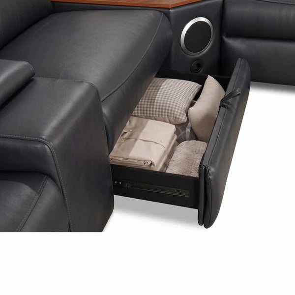 Aurelia Modern Air Leather Sectional Sofa Powered Recliner A close-up of a black leather reclining sofa seat with the storage compartment pulled open, showing folded bedding and pillows inside.