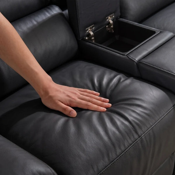 Aurelia Modern Air Leather Sectional Sofa Powered Recliner Close-up of a person's hand pressing down on the padded black leather seat of an armchair, with part of the armrest and a storage compartment visible.