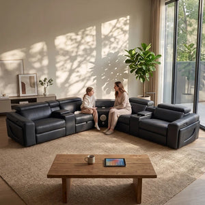 Aurelia Modern Air Leather Sectional Sofa Powered Recliner A modern U-shaped black leather sectional sofa in a bright, sunlit living room with a wooden coffee table, a woman, and a child sitting on the sofa, and a large potted plant near the window.