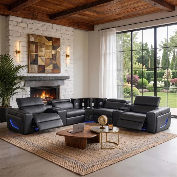Aurelia Modern Air Leather Sectional Sofa Powered Recliner A large black leather reclining sectional sofa with built-in media console and side lighting, staged in a modern living room with a fireplace, stone wall, large windows, and outdoor greenery visible.