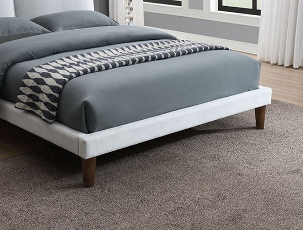 Bassetti Modern Style Shelter Padded White Bed Bed with gray bedding and wooden legs in a room with large windows.