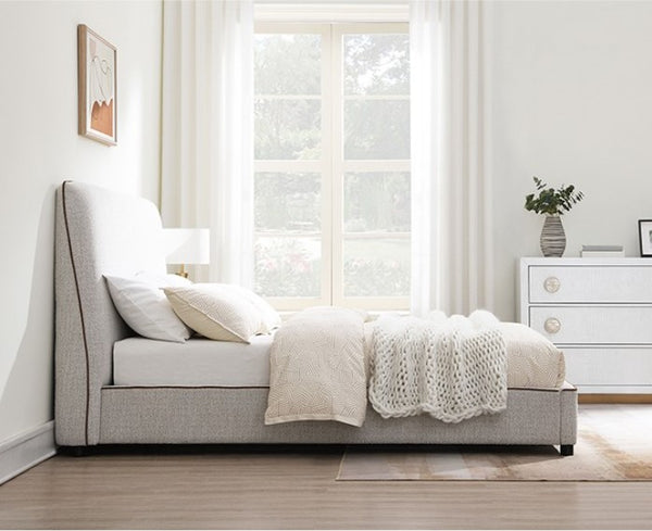 Bella Fully Upholstered Polyester Bed Neatly made bed in a bedroom with a large window and white dresser.