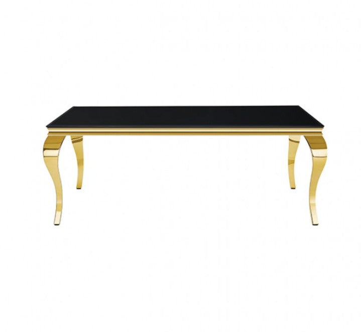 Betsy Black Glass Top Modern Dining Table A modern dining room set featuring a rectangular black table with gold legs and six matching black velvet chairs with gold legs, arranged on a light beige rug in a bright room with a window and pendant light.
