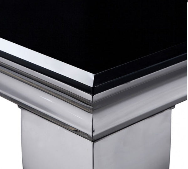 Betsy Silver Black Glass Top Modern Dining Room Table Close-up of a polished chrome pedestal table corner with a glossy black top surface.