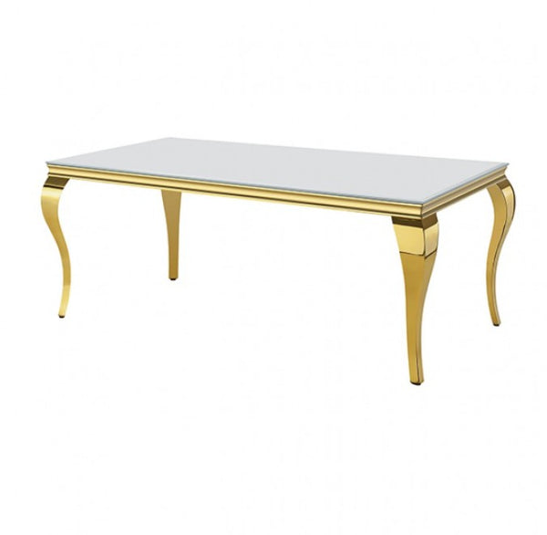 A rectangular dining table featuring a glossy white glass top and ornate, curved gold legs with a polished gold trim, shown on a solid white background.