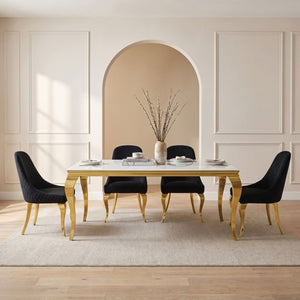 Betsy White Glass Top Modern Dining Table A modern dining set featuring a rectangular table with a white marble top and gold legs, surrounded by four black velvet upholstered chairs with gold legs, set on a light beige rug in a minimalist room with cream walls and an arched alcove.