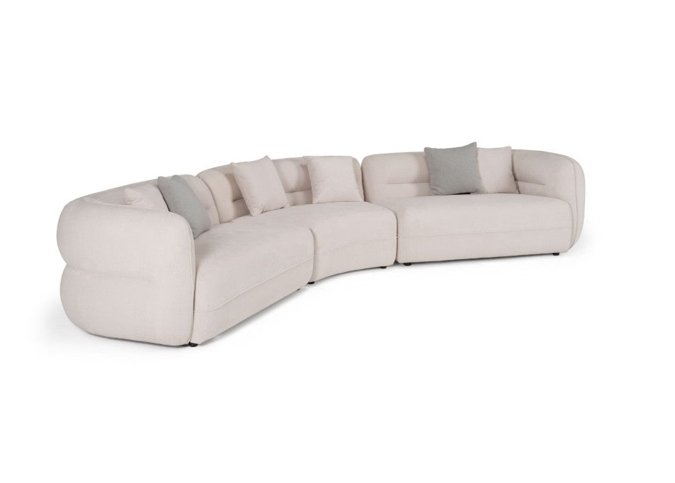 Boniser Modern Curved Off White Sectional Sofa A luxurious white curved modular sofa in a grand, elegant room with warm gold and cream lighting, a round wooden coffee table, and a beige rug.