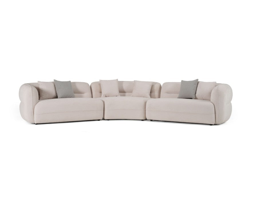 Boniser Modern Curved Off White Sectional Sofa A luxurious white curved modular sofa in a grand, elegant room with warm gold and cream lighting, a round wooden coffee table, and a beige rug.