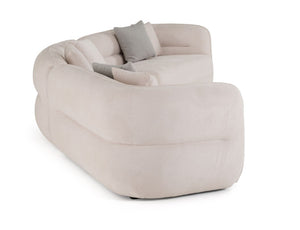 Boniser Modern Curved Off White Sectional Sofa A modern curved modular sofa upholstered in a soft blush-beige fabric, featuring two light gray accent pillows, shown on a solid white background.