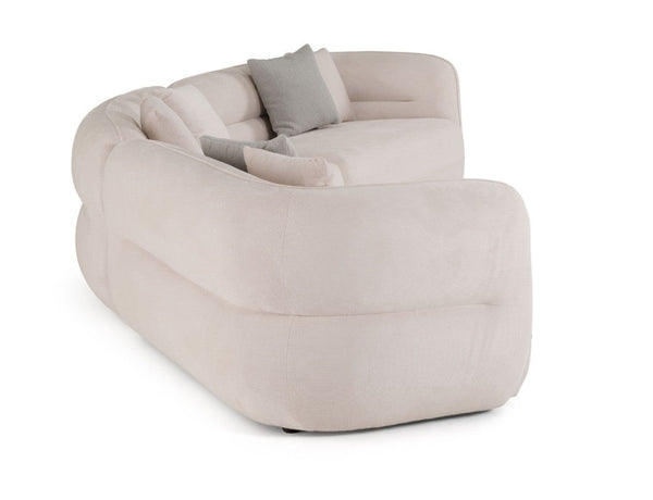 Boniser Modern Curved Off White Sectional Sofa A modern curved modular sofa upholstered in a soft blush-beige fabric, featuring two light gray accent pillows, shown on a solid white background.