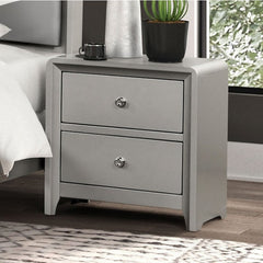 Borch Contemporary Champagne Finish Nightstand A light gray two-drawer nightstand with round silver knobs, shown in a bedroom setting next to a bed with white bedding and a potted plant on top.