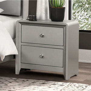 Borch Contemporary Champagne Finish Nightstand A light gray two-drawer nightstand with round silver knobs, shown in a bedroom setting next to a bed with white bedding and a potted plant on top.