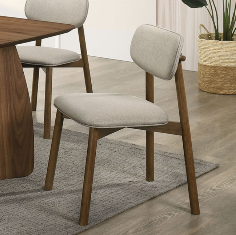 Bringa Walnut Beige Mid Century Modern Dining Chair A modern dining chair with a light beige upholstered seat and backrest on a medium brown wooden frame, shown in a styled dining room setting next to a wooden table.