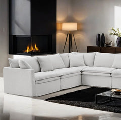 Bryant Sectional Sofa Linen Light Gray Fabric Modern living room with a white sectional sofa, fireplace, and decorative items.