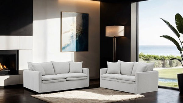 Bryant Sofa Linen Light Gray Fabric Modern living room with white sofas, a fireplace, and large windows.