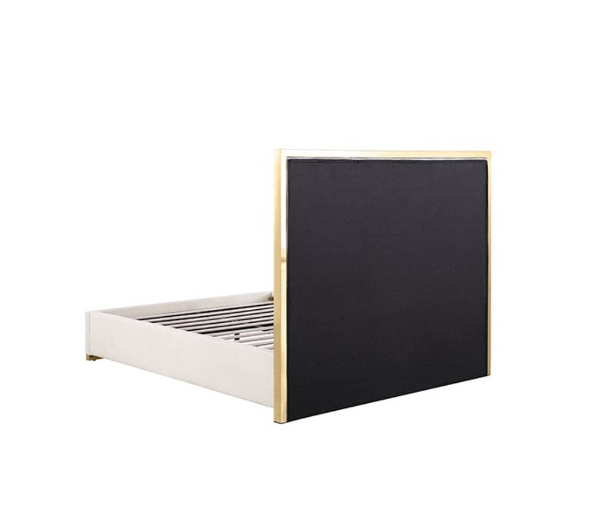 Burton Contemporary Glam White Gold Upholstered Bed A modern white upholstered bed with a geometric gold metal frame headboard, styled in a bright bedroom with white bedding, matching nightstands, gold lamps, and a gold ring pendant light.