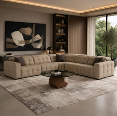 Carney 3 Recliners Beige Leather Modern Sectional Sofa A modern tufted beige sectional sofa arranged in an L-shape in a stylishly decorated living room with a glass-top coffee table, textured rug, shelving, and large windows.