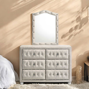 Chloe Beige Fabric Full Upholstered Kids Dresser A light beige upholstered dresser with six drawers and a matching arched mirror, both featuring tufted detailing and silver-tone nailhead trim, set against a warm beige wall with soft shadow patterns.