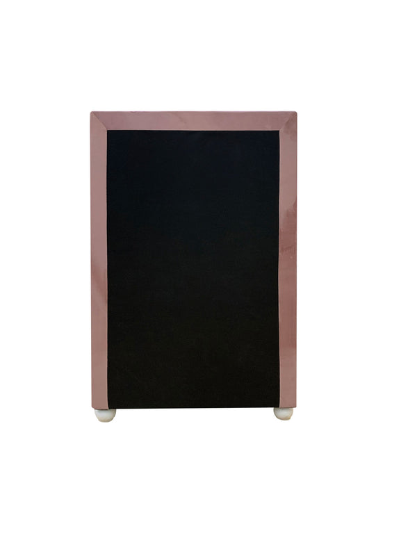 Chloe Pink Fabric Full Upholstered Kids Chest A small black chalkboard with a glossy rose gold or dusty pink frame, standing on small white feet against a plain white background.