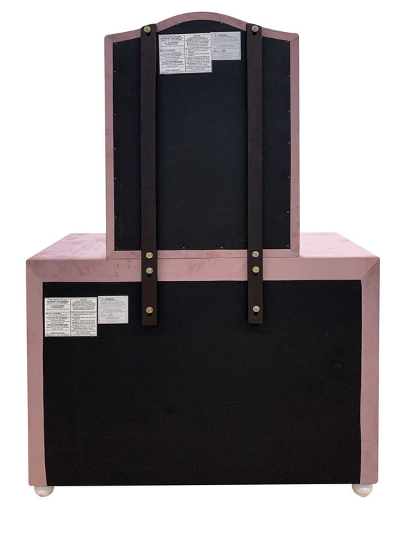 Chloe Pink Fabric Full Upholstered Kids Dresser The back view of a vintage vanity cabinet with a dusty pink frame and black fabric-covered panels, featuring dark brown wooden support straps and white feet.