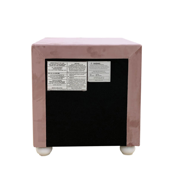 Chloe Pink Fabric Full Upholstered Kids Nightstand A square upholstered ottoman or small bench with a dusty pink velvet-like fabric cover, a large black front panel, and two small white feet. Product labels are visible on the front panel.